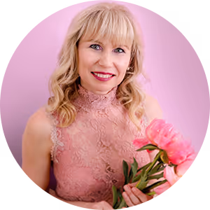 Smiling blonde woman in a pink lace dress holds pink peonies in front of a pink background, Veronika Mutti, author