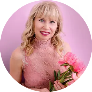 Smiling blonde woman in a pink lace dress holds pink peonies in front of a pink background, Veronika Mutti, author